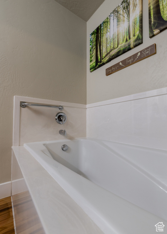 Full bath featuring a garden tub, baseboards, and wood finished floors
