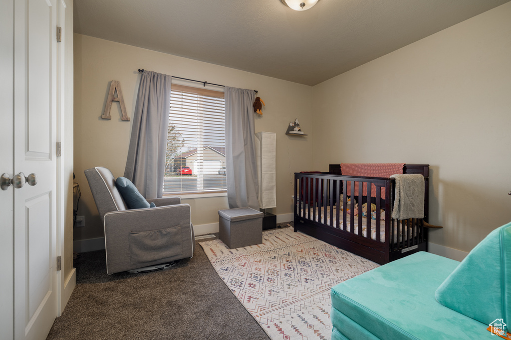Bedroom with baseboards, carpet flooring, and a crib