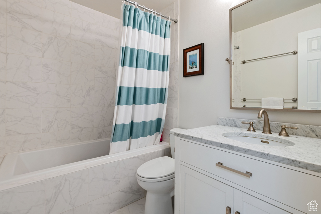 Full bathroom featuring shower / tub combo, toilet, marble look tile flooring, and vanity