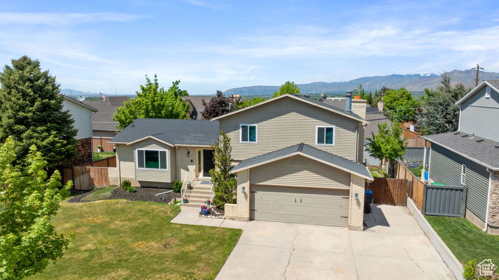 Tri-level home with brick siding, driveway, a garage, and a mountain view
