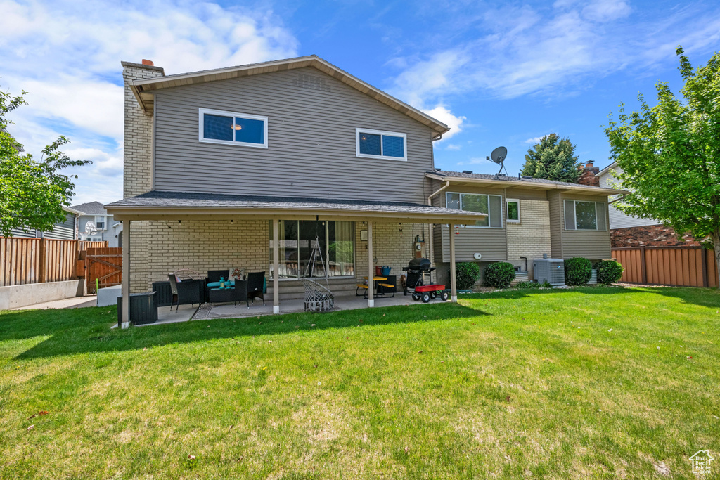 Back of property with a patio area, a chimney, cooling unit, and brick siding