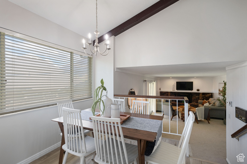 Dining room with a chandelier, beamed ceiling, a fireplace, high vaulted ceiling, and wood finished floors