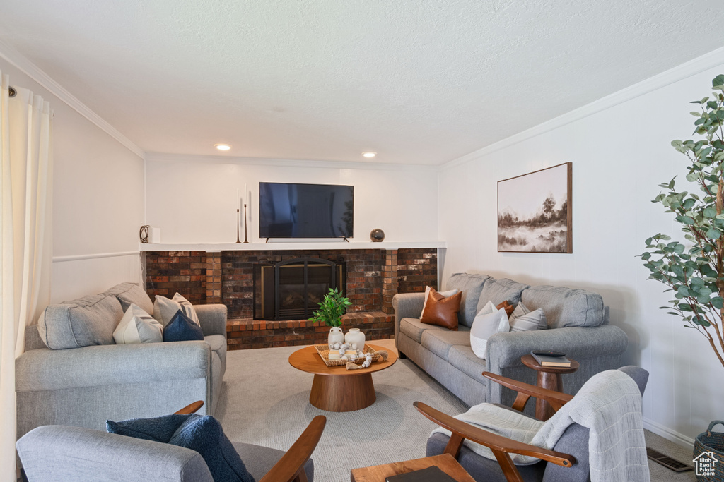 Carpeted living area featuring crown molding, a brick fireplace, and recessed lighting