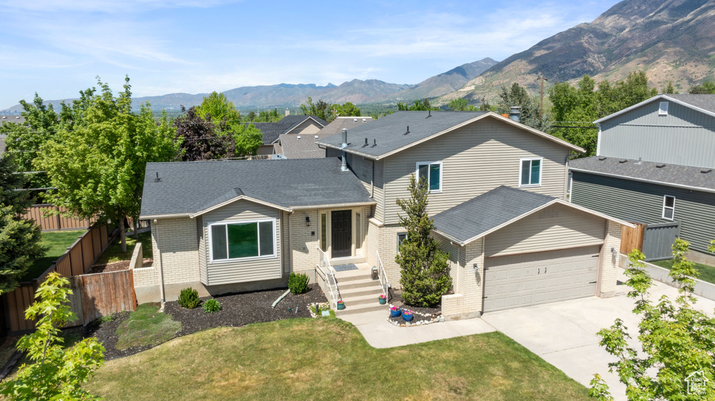 View of front of property with driveway, a mountain view, brick siding, and a garage