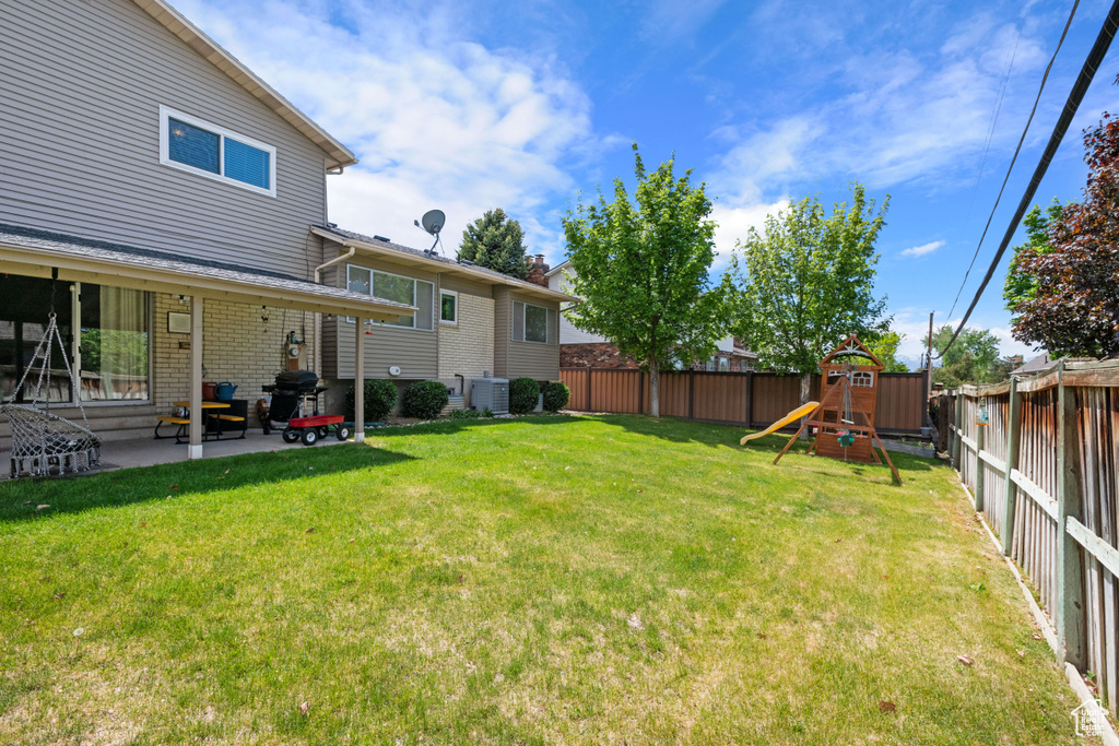 View of yard featuring a patio area, a playground, and central AC unit