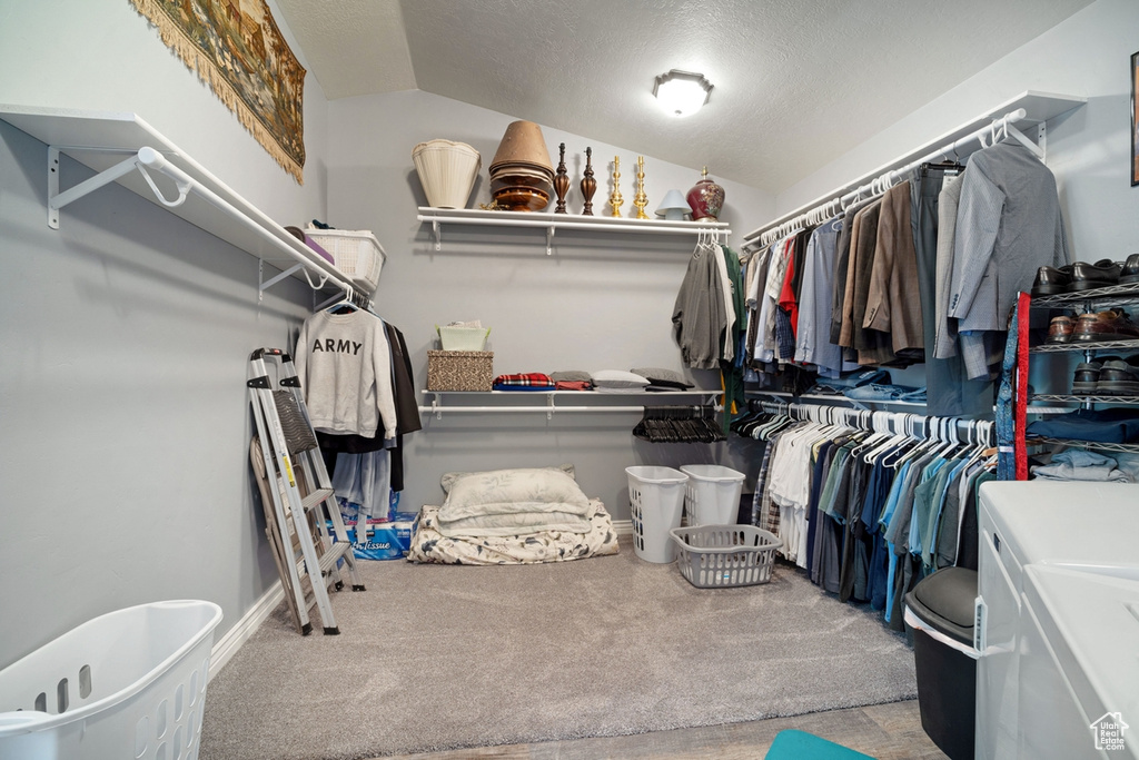 Walk in closet featuring lofted ceiling, washer and dryer, and carpet