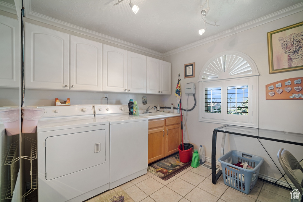 Washroom with washer and dryer, cabinet space, rail lighting, light tile patterned flooring, and ornamental molding