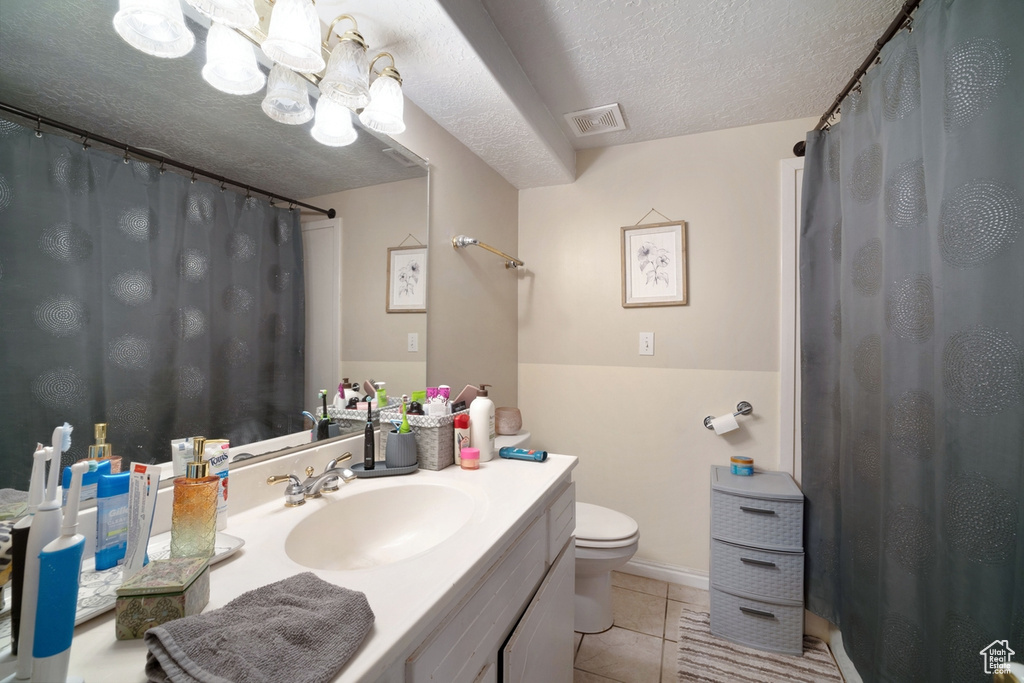 Bathroom featuring tile patterned flooring, toilet, a textured ceiling, vanity, and a chandelier