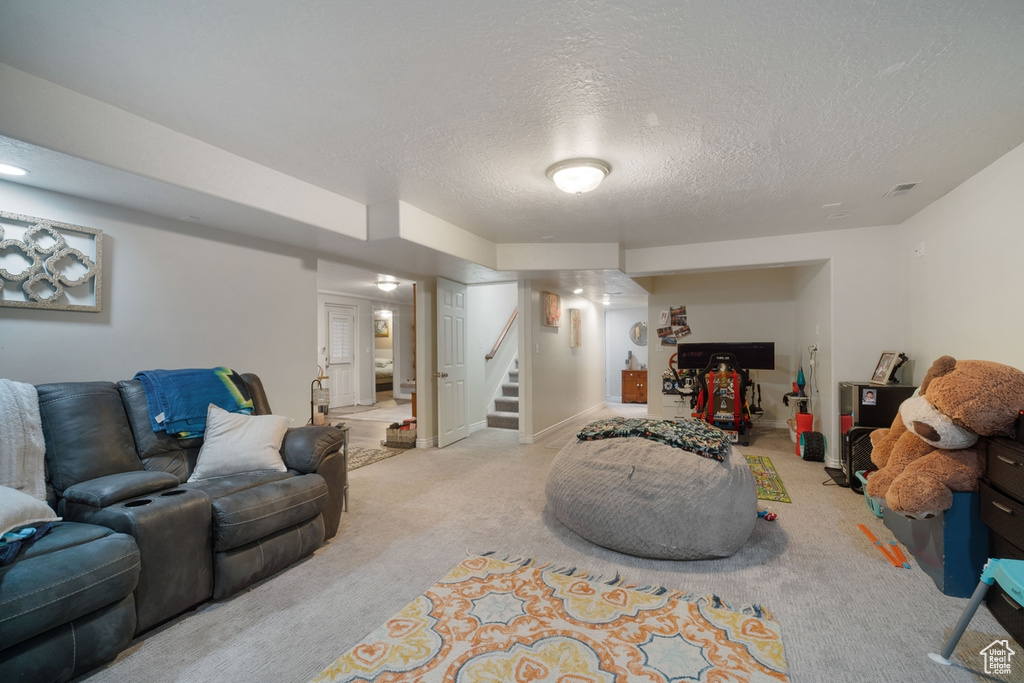 Living room featuring carpet, a textured ceiling, and stairs