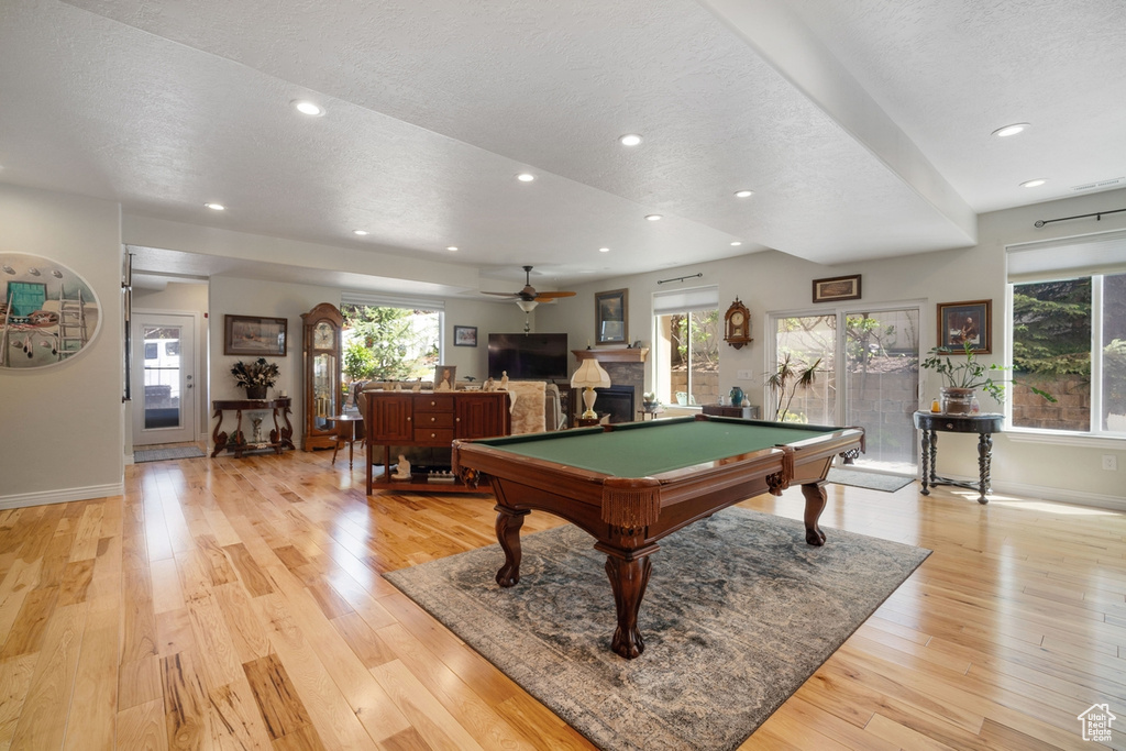 Recreation room featuring a textured ceiling, baseboards, light wood-style flooring, ceiling fan, and pool table