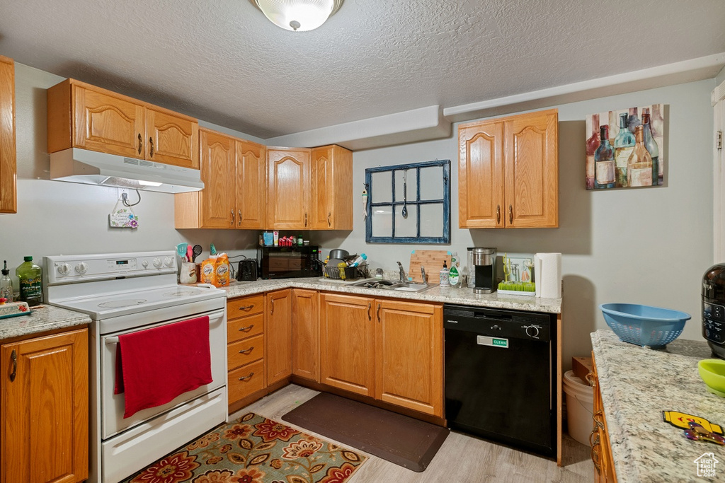 Kitchen featuring electric range, under cabinet range hood, black dishwasher, a sink, and a textured ceiling