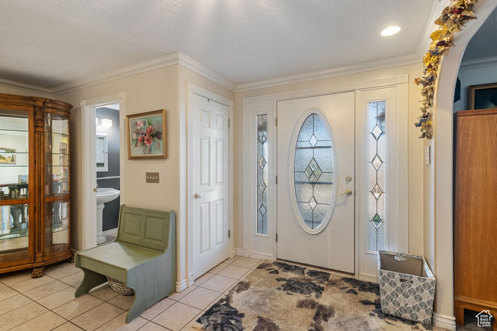 Entryway with light tile patterned flooring and crown molding