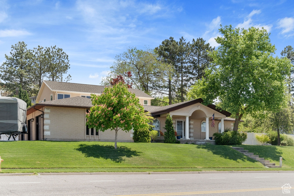 View of front of property featuring brick siding, a front yard, an attached garage, and a shingled roof
