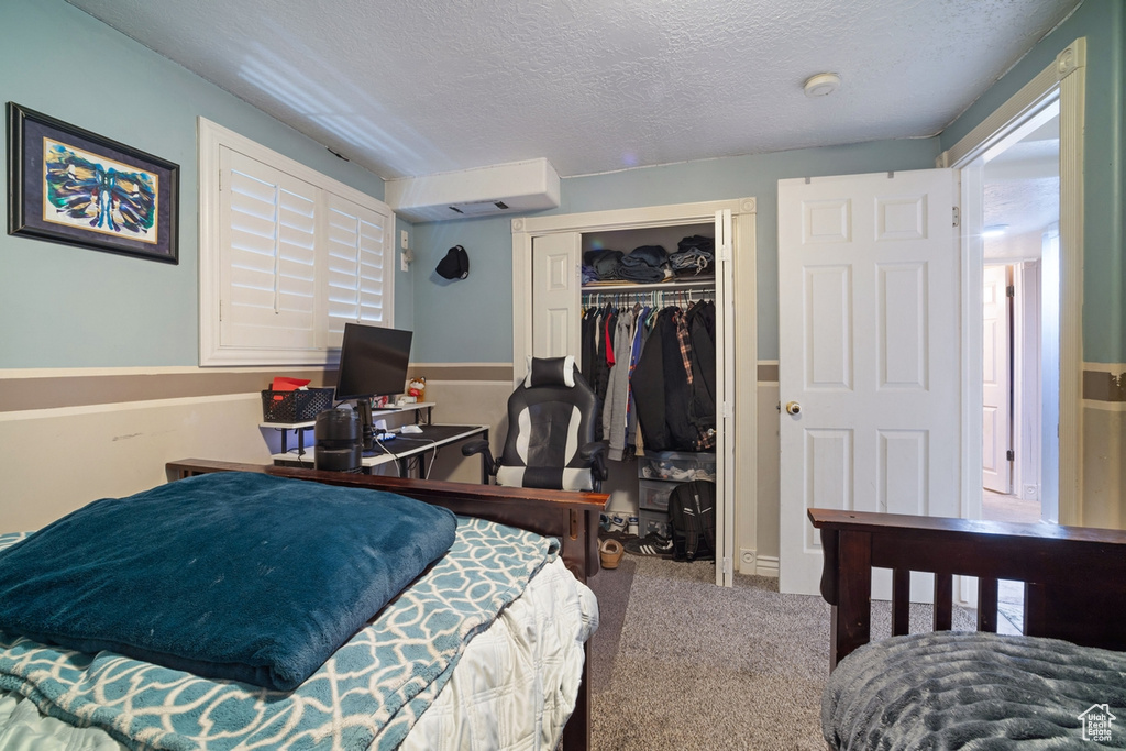Carpeted bedroom with a textured ceiling and a closet