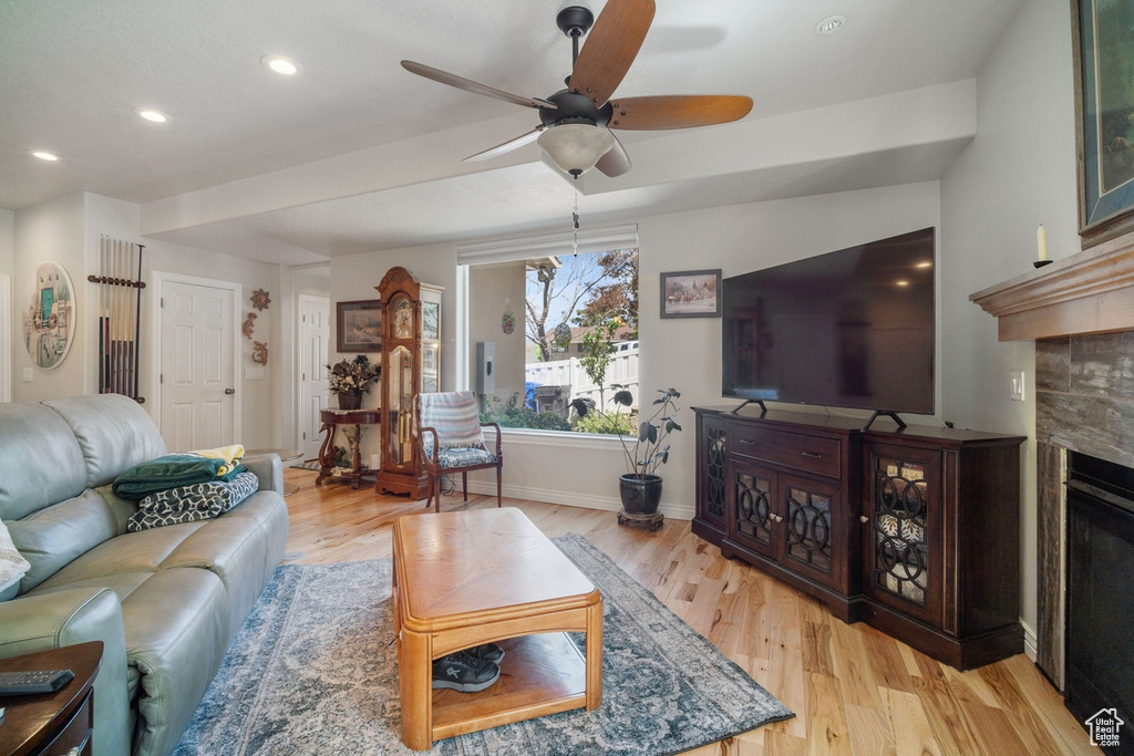 Living area featuring light wood-style floors, a ceiling fan, baseboards, recessed lighting, and a fireplace
