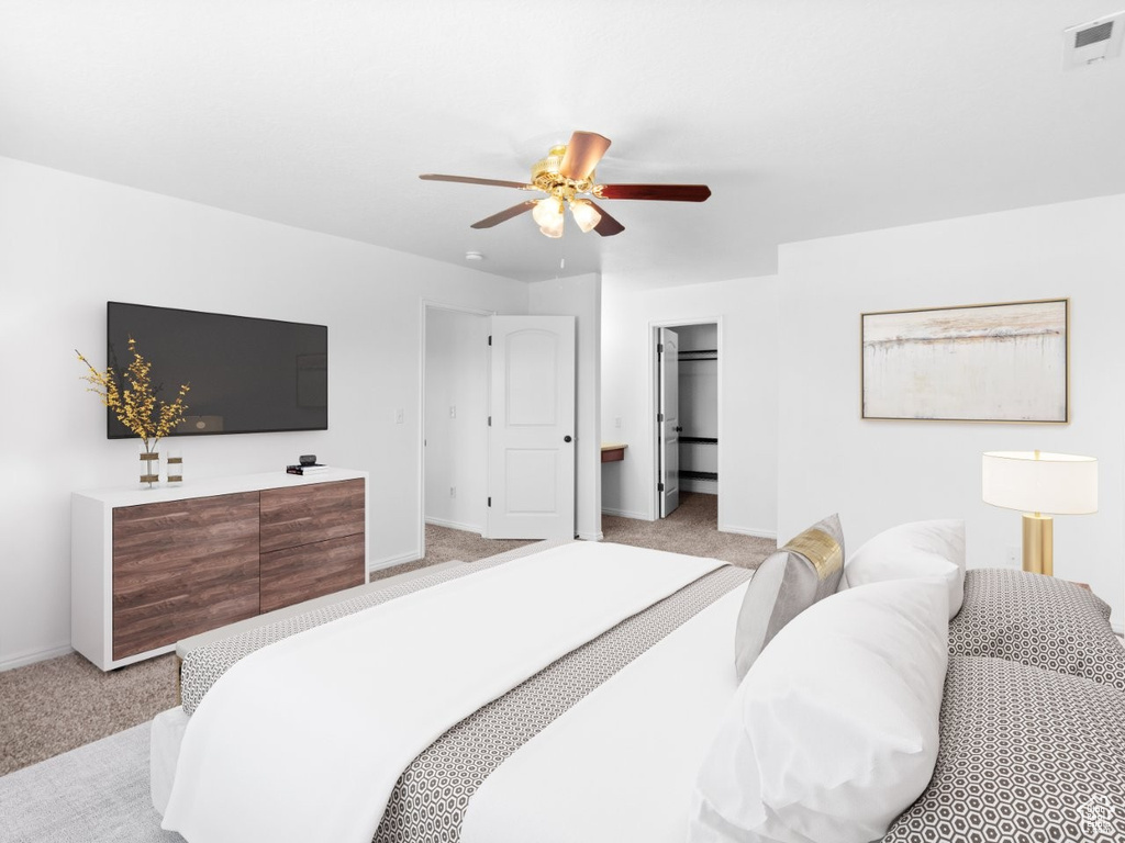 Bedroom featuring light carpet, baseboards, a ceiling fan, and a walk in closet