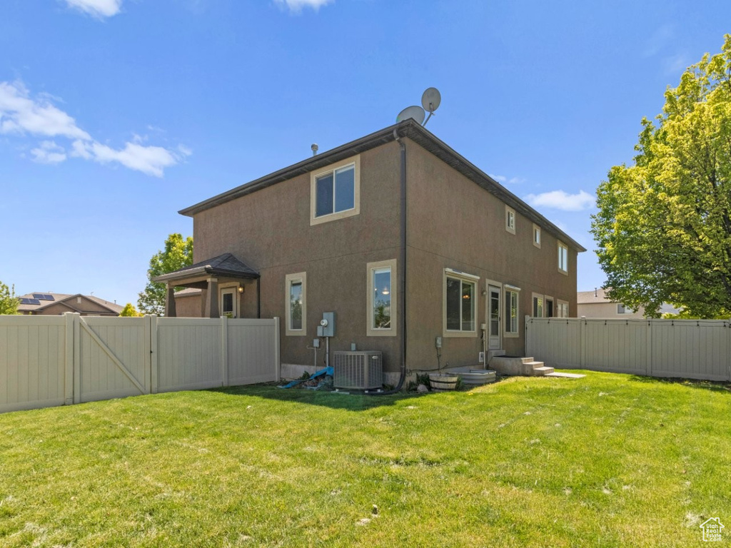 Rear view of house with a gate, cooling unit, and stucco siding