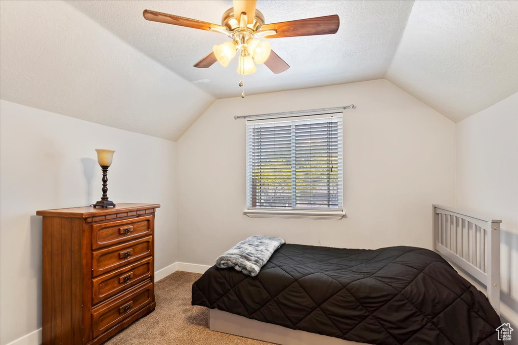 Bedroom with vaulted ceiling, carpet, baseboards, and a ceiling fan