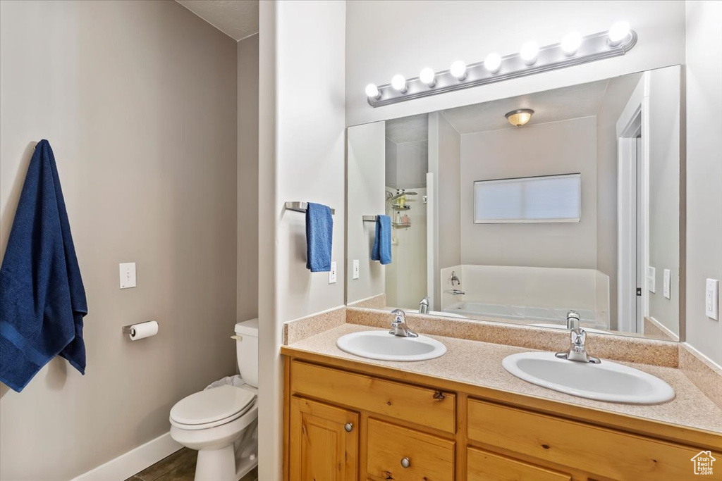 Full bathroom with toilet, double vanity, and a bathtub