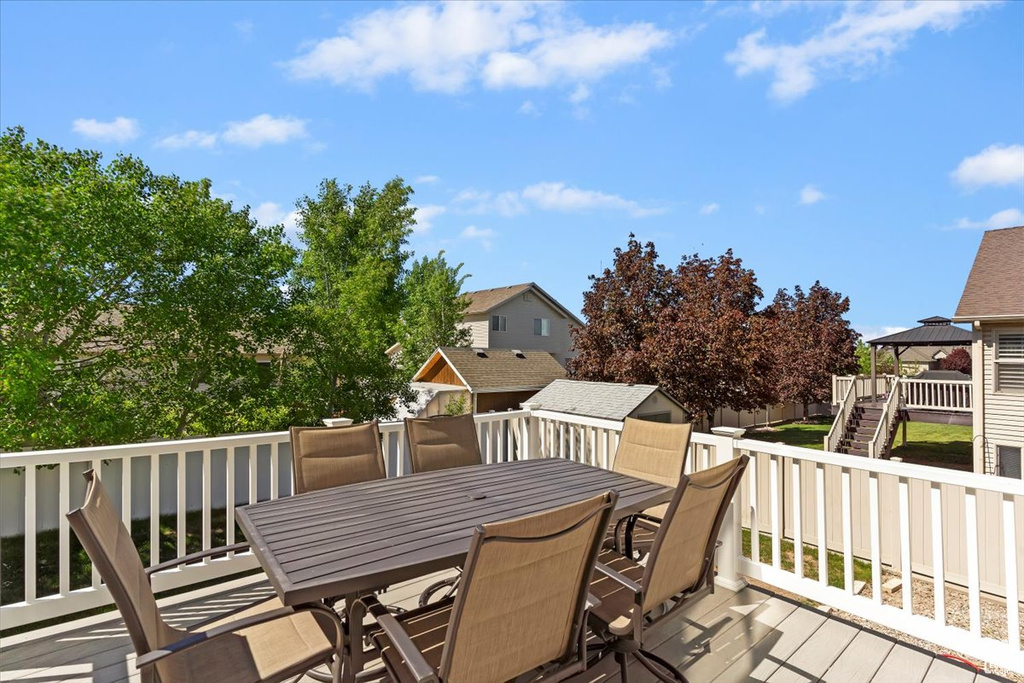 Wooden terrace featuring outdoor dining area and a storage unit