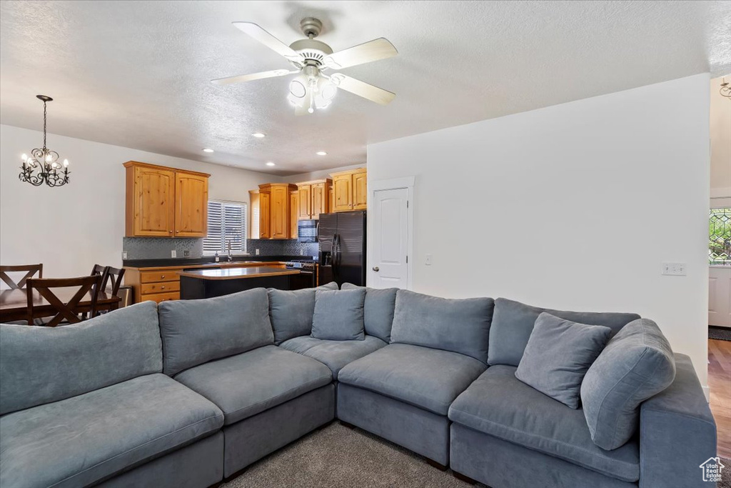 Living room featuring ceiling fan, recessed lighting, a chandelier, wood finished floors, and a textured ceiling