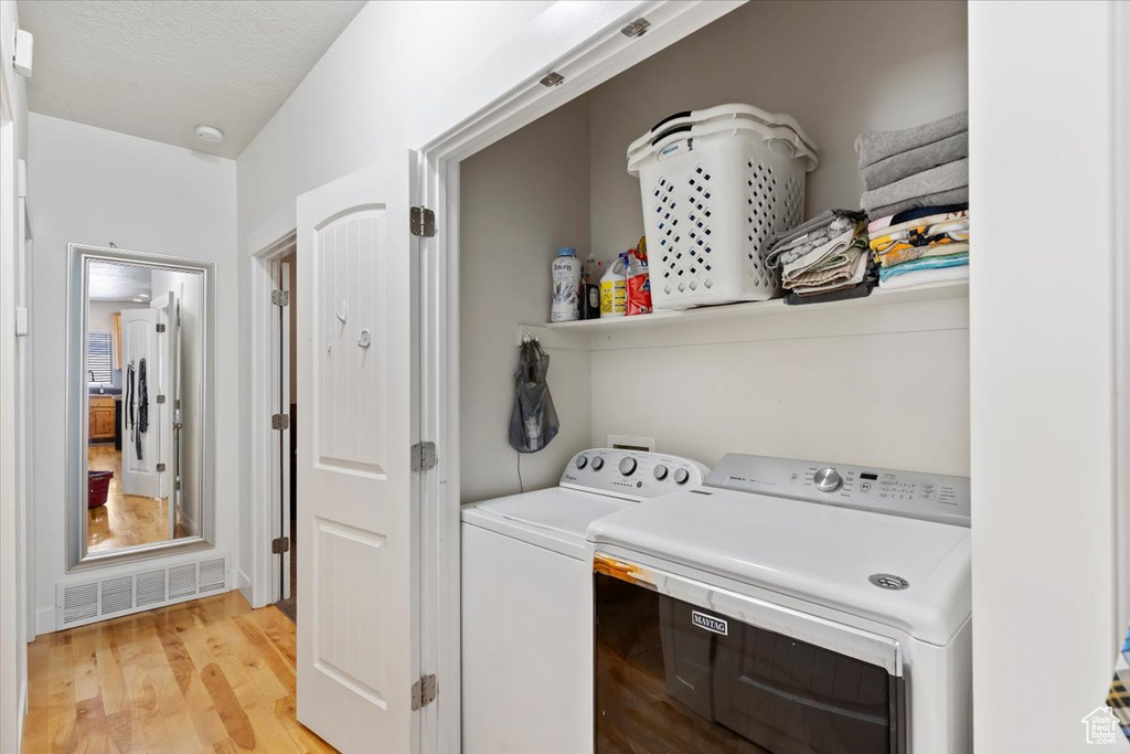 Clothes washing area featuring washer and dryer and light wood finished floors