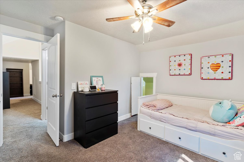 Carpeted bedroom featuring ceiling fan and baseboards