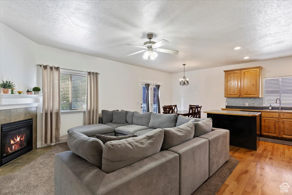 Living area with a ceiling fan, a textured ceiling, a fireplace, a chandelier, and recessed lighting