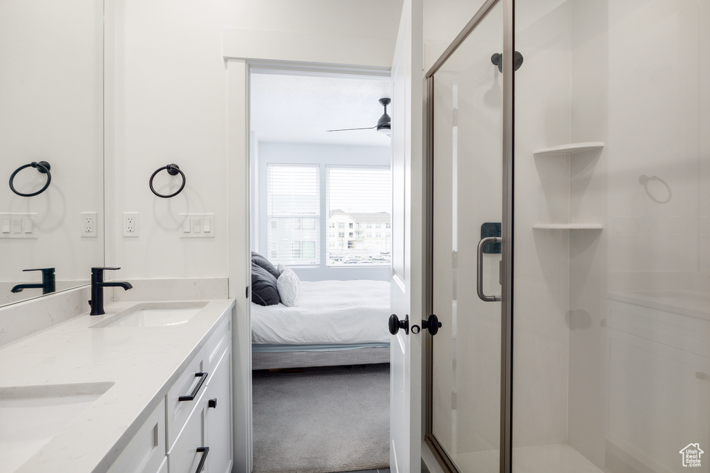 Ensuite bathroom featuring a shower stall, a ceiling fan, and double vanity