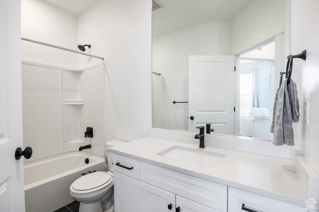 Bathroom with toilet, vanity, and  shower combination