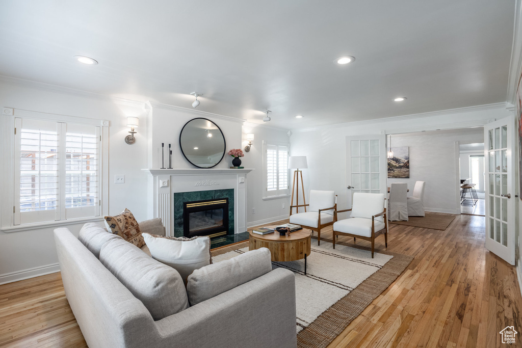 Living room featuring ornamental molding, a high end fireplace, baseboards, wood finished floors, and recessed lighting