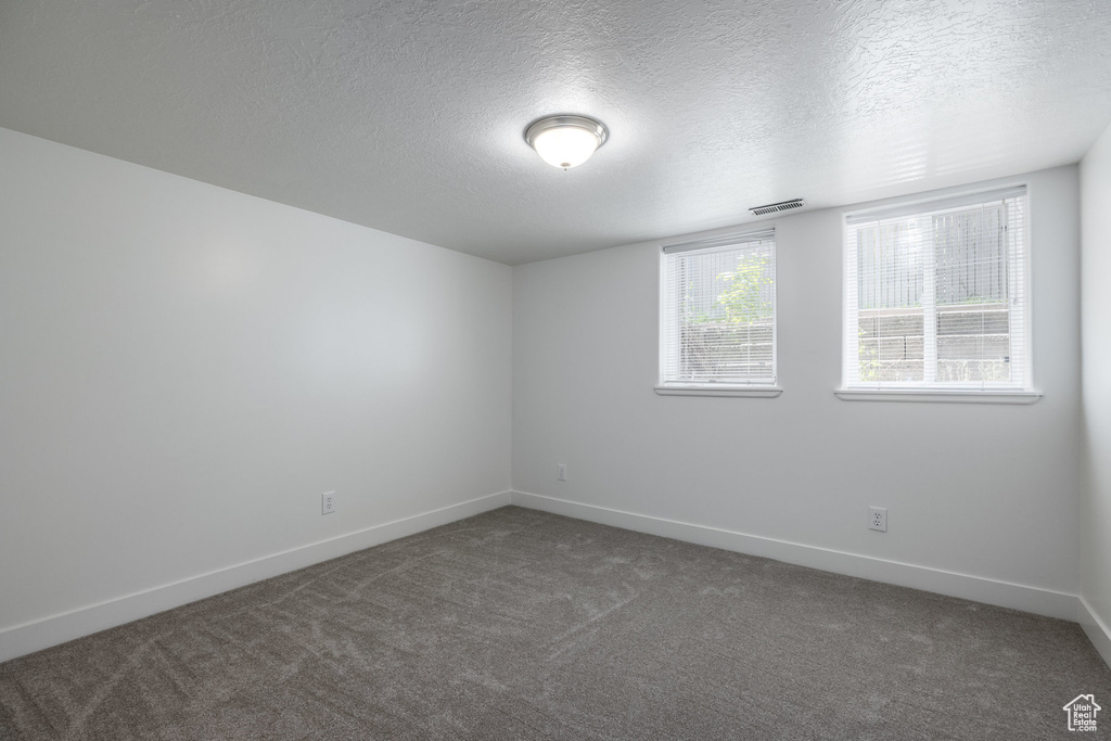 Carpeted spare room featuring baseboards and a textured ceiling