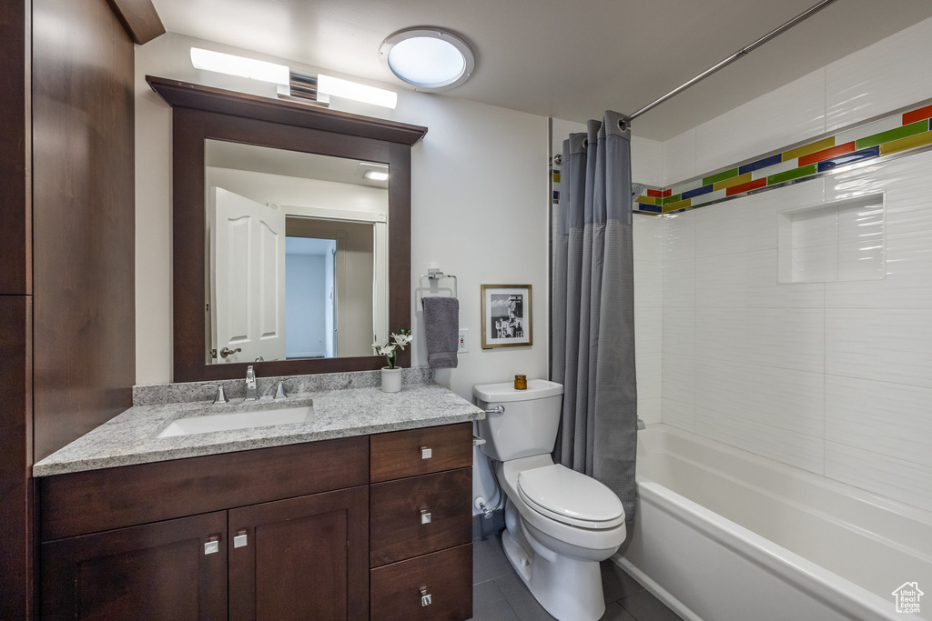 Full bath featuring tile patterned flooring, toilet, vanity, and shower / tub combo with curtain