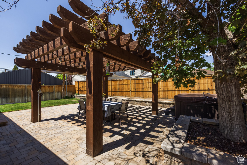 View of patio / terrace with a hot tub, a pergola, a fenced backyard, and outdoor dining space