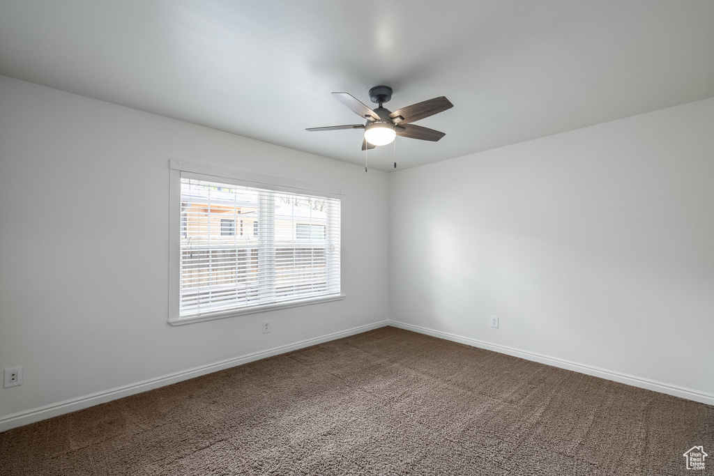 Empty room with ceiling fan, carpet flooring, and baseboards