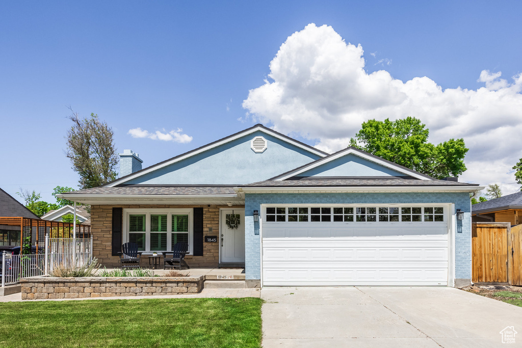 Ranch-style home with an attached garage, driveway, covered porch, and a chimney