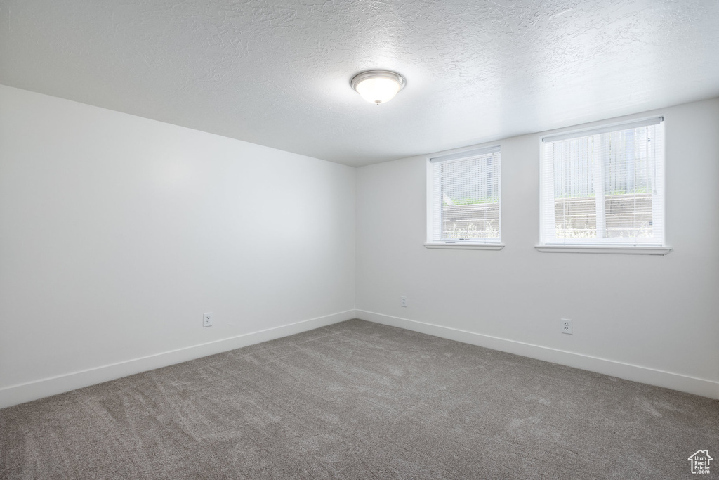 Carpeted spare room featuring baseboards and a textured ceiling