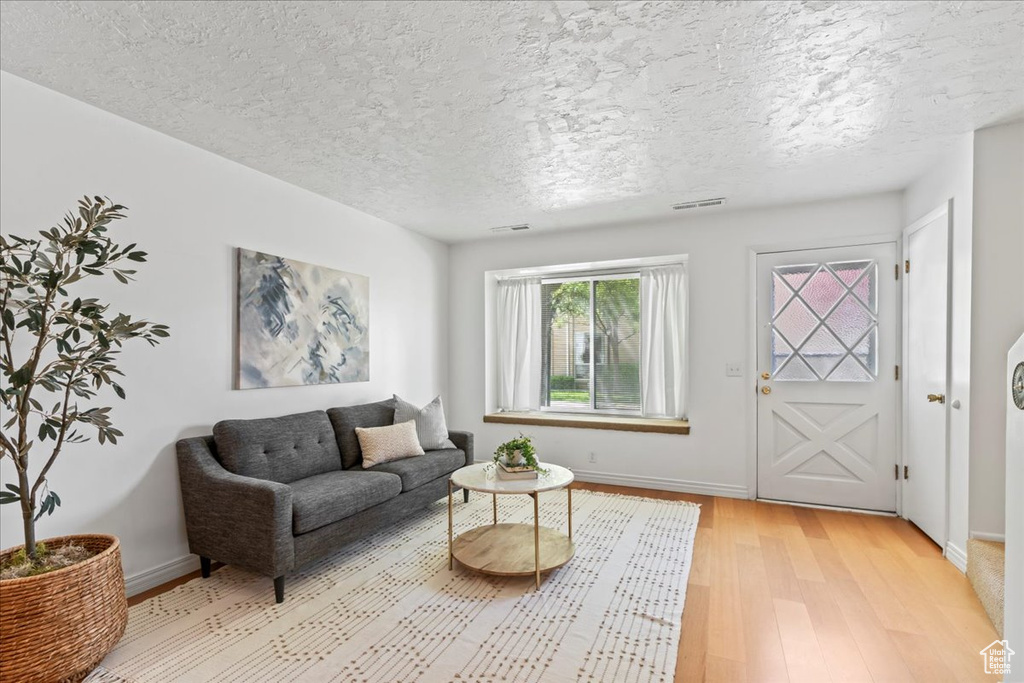 Living area featuring light wood finished floors, baseboards, and a textured ceiling