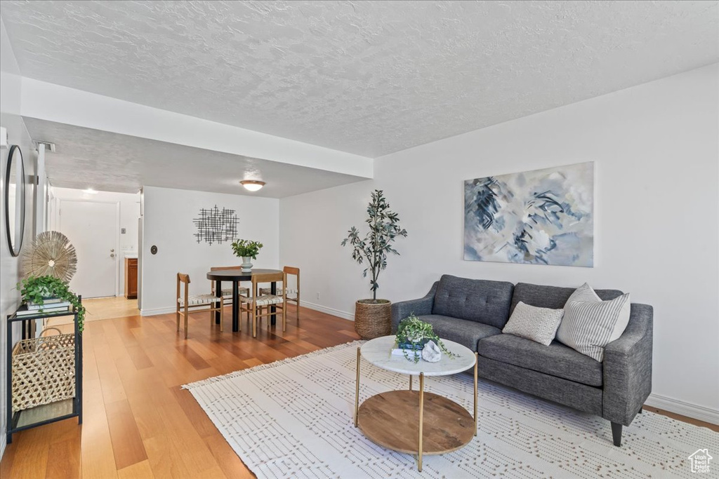 Living area with light wood-style flooring, baseboards, and a textured ceiling
