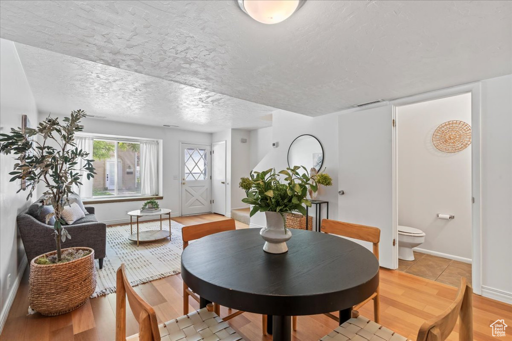 Dining space featuring light wood-type flooring, a textured ceiling, and baseboards