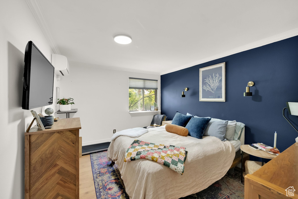 Bedroom with crown molding, a wall unit AC, and wood finished floors