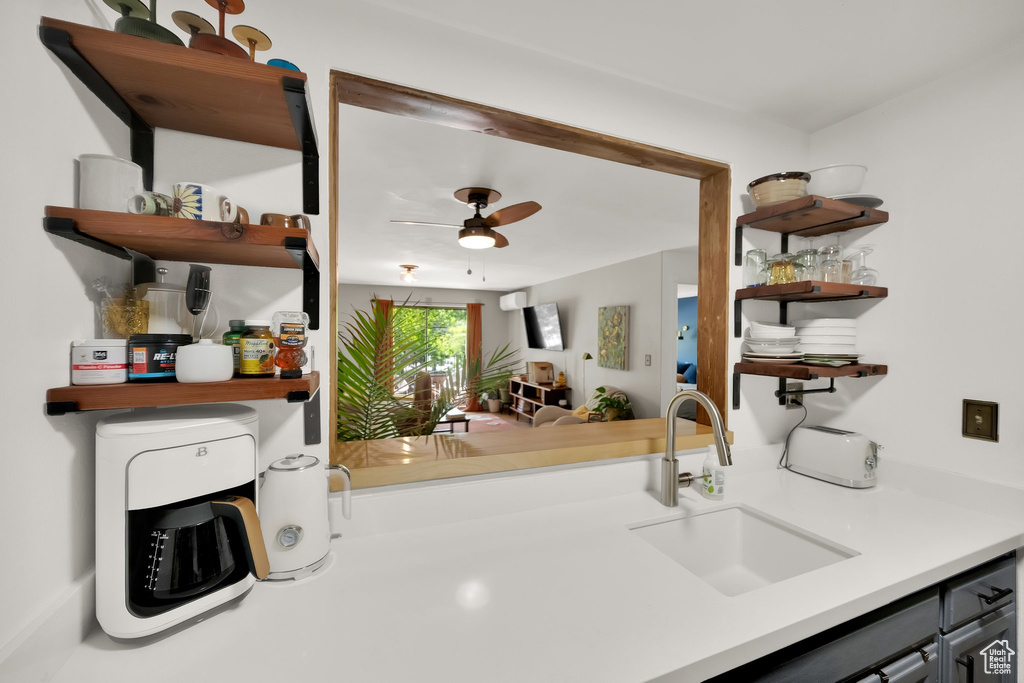 Kitchen with a sink, open shelves, ceiling fan, and light countertops