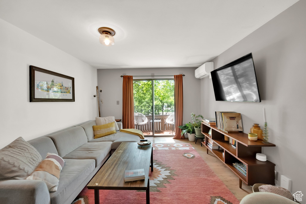 Living area featuring light wood-style floors and a wall mounted air conditioner