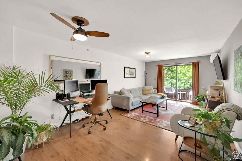 Living area with wood finished floors, a desk, and a ceiling fan