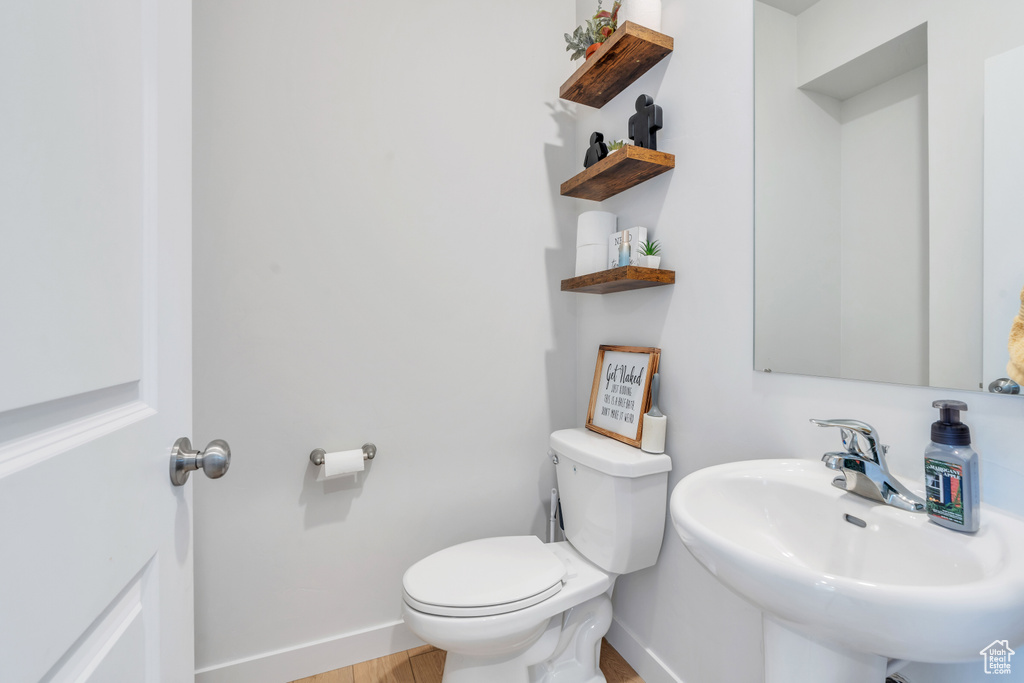Bathroom with a sink, baseboards, toilet, and wood finished floors