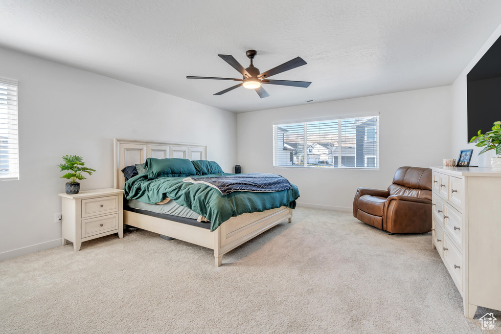 Bedroom featuring light carpet, baseboards, and ceiling fan