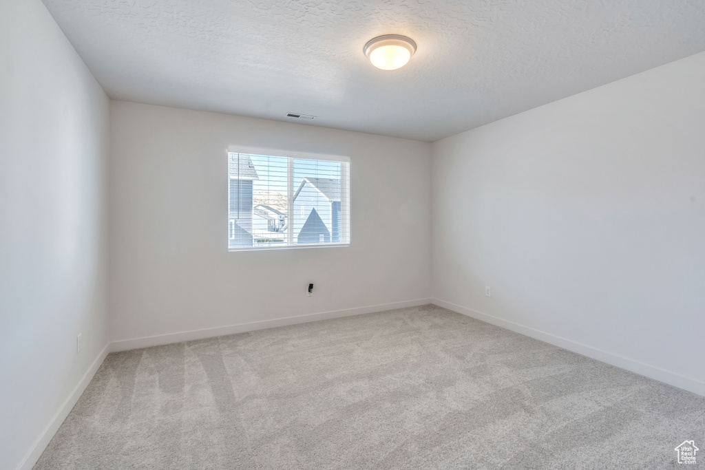 Empty room with carpet floors, a textured ceiling, and baseboards