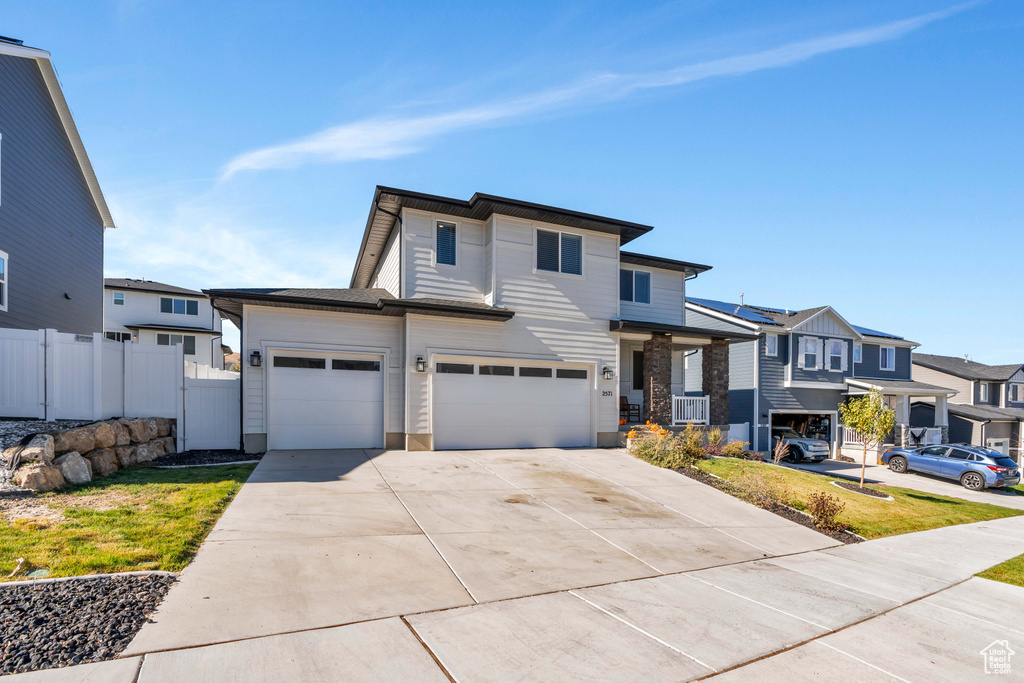 View of front of home with fence, driveway, a residential view, and an attached garage