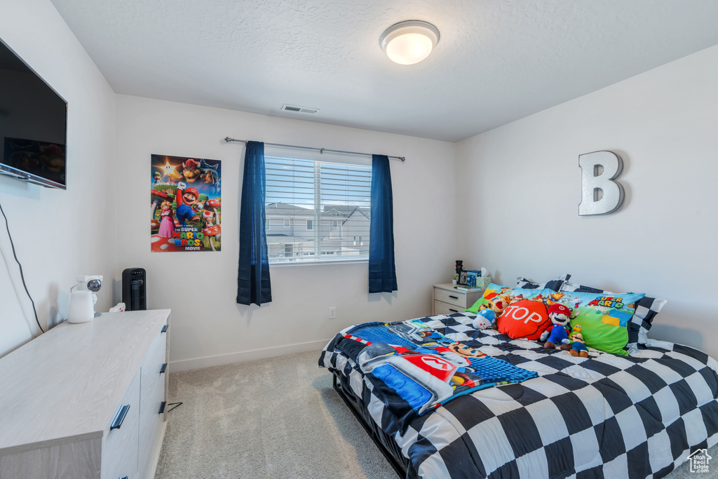 Bedroom with light carpet, baseboards, and a textured ceiling