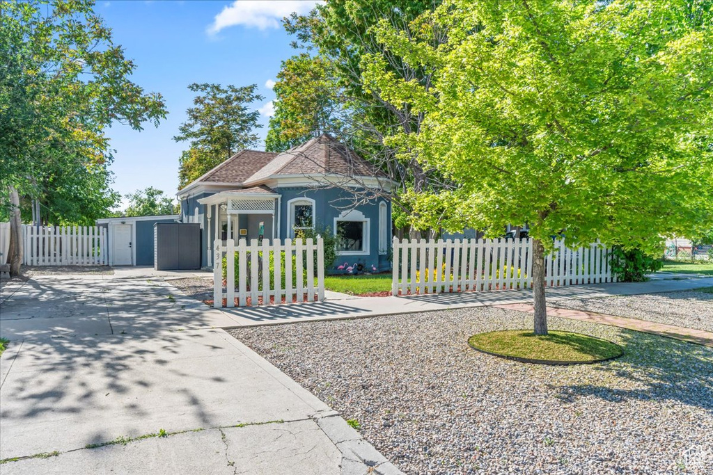 View of front of property featuring stucco siding, a gate, driveway, and a fenced front yard